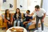Vibrant social gathering in a modern apartment living room, with friends enjoying drinks and charcuterie board on a stylish coffee table.
