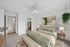 Inviting bedroom with modern decor, featuring a lush plant, cozy bed with green accents, and walk-in closet.
