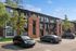 Modern apartment complex with brick accents and ample parking space, surrounded by lush greenery.