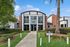 Inviting leasing office exterior with modern architecture, lush landscaping, and palm trees, perfect for future residents.