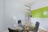 Modern study room with elegant glass table, stylish chairs, and vibrant green accent wall.