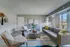 Chic living room with cozy grey furniture, accent pillows, stylish decor, and sunlit balcony view.