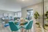 Chic apartment interior featuring a modern dining area with teal chairs, elegant table settings, and a cozy living space with stylish decor and natural lighting.