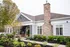 Charming single-story home with elegant stone facade, large windows, and lush landscaped garden.