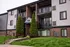 Charming apartment building with modern brick facade, private balconies, and lush landscaped entrance.