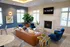 Elegant lounge area with modern decor, featuring a cozy fireplace, plush seating, and vibrant greenery in a sunlit room.