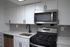 Modern kitchen with sleek stainless steel appliances, elegant white cabinetry, and stylish gray tile backsplash.