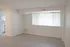 Bright and inviting living space with large window, sleek laminate flooring, and open access to a modern kitchen.
