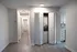 Modern hallway featuring elegant wood flooring, built-in laundry area with chic sliding doors, and streamlined kitchen entry with sleek cabinetry.