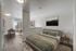 Bright and airy apartment bedroom with elegant decor, featuring a cozy bed, modern side table, and open view dining area with floor-to-ceiling windows.