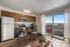 Bright and modern kitchen-dining area with sleek appliances and panoramic city view through large balcony doors.