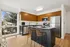 Sleek and modern kitchen with stainless steel appliances, stylish wood cabinetry, and a cozy breakfast bar under natural lighting.
