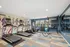 Modern fitness center with sleek treadmills, weight rack, vibrant wall art, and natural light for an energizing workout experience.