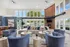 Elegant living room with modern decor, featuring plush couches, stylish armchairs, and a cozy fireplace set against a striking brick wall. Large windows flood the space with natural light, enhancing its open and inviting atmosphere.
