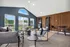 Bright and stylish living area with sleek modern furniture, large windows, and dartboards, accentuated by rich wood paneling.