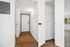 Inviting apartment entryway featuring stylish wood flooring, bright white walls, and modern fixtures.