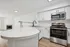 Modern kitchen with sleek appliances, spacious countertops, and open layout extending to a cozy living area with a fireplace.