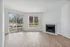 Bright living room with elegant hardwood flooring, large windows for natural light, and a cozy fireplace, perfect for relaxation.