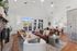 Elegant living room with high vaulted ceilings, featuring a cozy fireplace, modern furniture, and large windows opening to a bright outdoor patio.