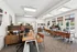 Modern, sunlit office with sleek wooden desks, stylish chairs, and lush greenery, offering an inviting and productive workspace.
