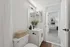 Bright and modern bathroom featuring sleek white cabinetry, elegant fixtures, and a stylish plant accent, seamlessly connected to a cozy adjacent room.
