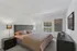 Bright and inviting bedroom featuring a comfortable bed with stylish linens, elegant bedside lamps, and large windows allowing natural light to fill the space.