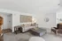Inviting living room with modern decor, featuring a cozy beige sofa, plush ottoman, and warm lighting, perfect for relaxation.
