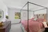 Elegant bedroom with a stylish four-poster bed, large window providing natural light, and chic decor for a cozy ambiance.
