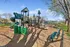 Inviting playground with green slides, adventurous climbing structures, and a serene park setting, perfect for family fun and outdoor activities.