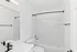 Contemporary bathroom with sleek black fixtures, pristine white tiles, and a bathtub, offering a modern and fresh design.