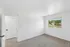 Bright and airy bedroom with plush carpet, large window with picturesque view, and modern white door.