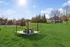 Refreshing outdoor space featuring a lush green lawn, a modern picnic area, and a scenic backdrop of elegant homes under a bright blue sky.