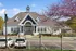 Charming clubhouse with classic architecture surrounded by vibrant landscaping and blooming trees, offering a welcoming community atmosphere.