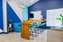 Modern workspace with vibrant blue accents, sleek wood desk, and stylish high chairs, perfect for creative collaboration.