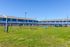 Charming apartment complex featuring vibrant blue exteriors and a spacious green dog park, perfect for pet lovers.