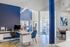 Inviting office space with modern decor featuring a sleek desk, ergonomic chairs, and ambient lighting against a vibrant blue accent wall.