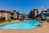 Elegant apartment complex showcasing a refreshing outdoor pool with stylish lounge chairs and vibrant landscaping under a clear blue sky.