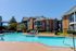 Inviting apartment complex with a sparkling outdoor pool, surrounded by sun loungers and lush greenery, perfect for relaxation.