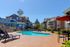 Modern apartment complex featuring stylish architecture and a sparkling outdoor pool area with lounge chairs, perfect for relaxation.