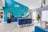 Modern kitchen with vibrant turquoise tiles, sleek island seating, and stylish lighting fixtures.