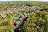 Stunning aerial view of a vibrant residential community nestled in lush greenery, featuring spacious apartment complexes and a tennis court, offering a perfect blend of nature and modern living.