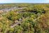 Serene aerial view of a lush, wooded residential area showcasing charming homes nestled among vibrant greenery, promising tranquility and nature-filled living.