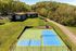 Aerial view of a vibrant apartment community with modern buildings, lush greenery, a blue tennis court, and a colorful playground.