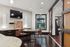 Modern communal area with sleek wooden flooring, stylish round table, and chairs, featuring a flat-screen TV and large window with outdoor views.