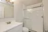 Modern bathroom featuring a sleek shower with glass doors, elegant white vanity, and stylish lighting.