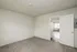 Bright and cozy room with plush carpet flooring, leading to a well-lit living space through an open door.