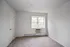 Bright and airy empty room with plush carpeting, fresh white walls, and a large window letting in natural light.