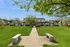 Charming community view of townhomes with lush green lawns, mature trees, and inviting benches on a sunny day.