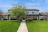 Charming two-story brick townhouse with vibrant landscaping and a welcoming pathway under a clear blue sky.