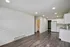 Bright modern apartment kitchen with sleek white cabinets and appliances, hardwood flooring, and recessed lighting.